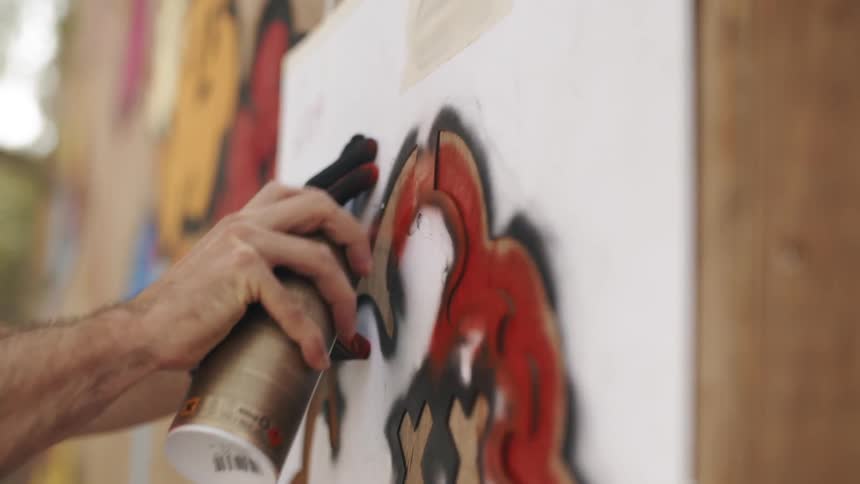 A man is spray painting a wall outdoors