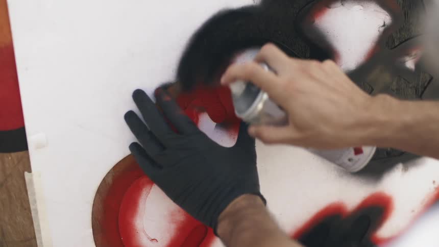 A man spray paints over a stencil