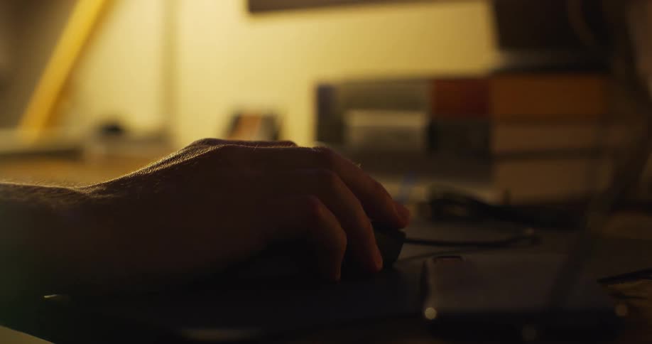 Person holds and clicks on mouse in dim light