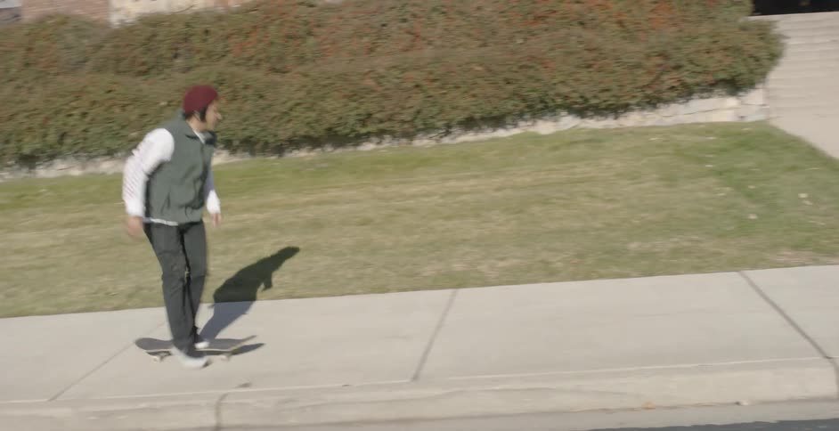 Man skateboarding up a sidewalk and towards steps