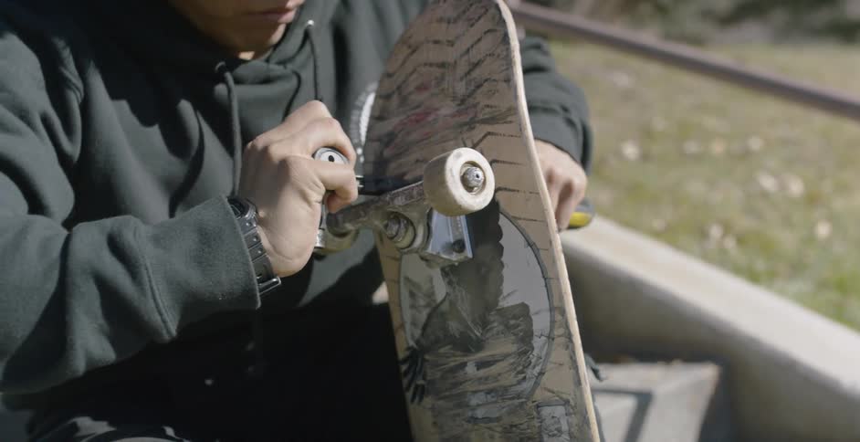 A man tightens wheels on a skateboard