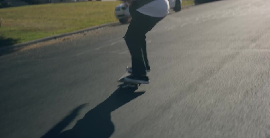 A person on a skateboard performing a trick on a black asphalt road
