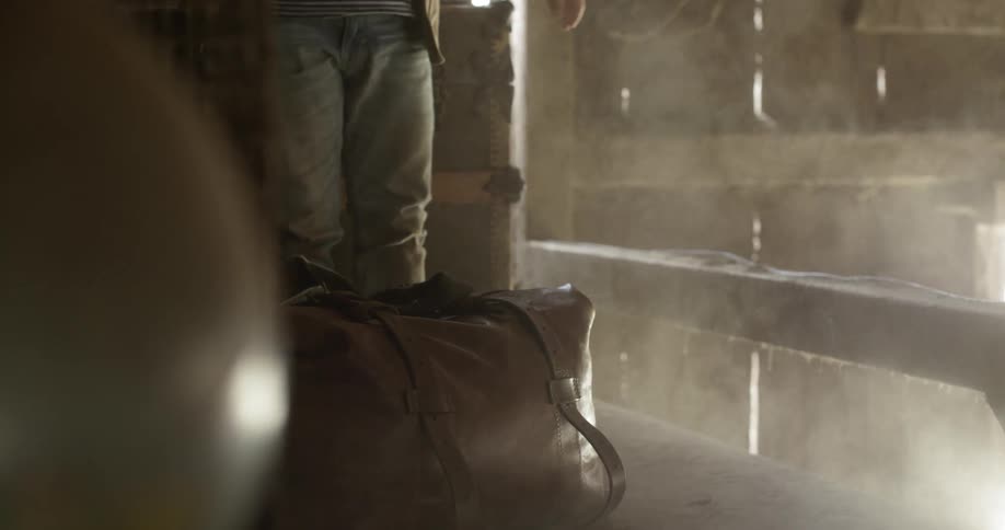 Man lifting and dropping a heavy leather bag in a barn