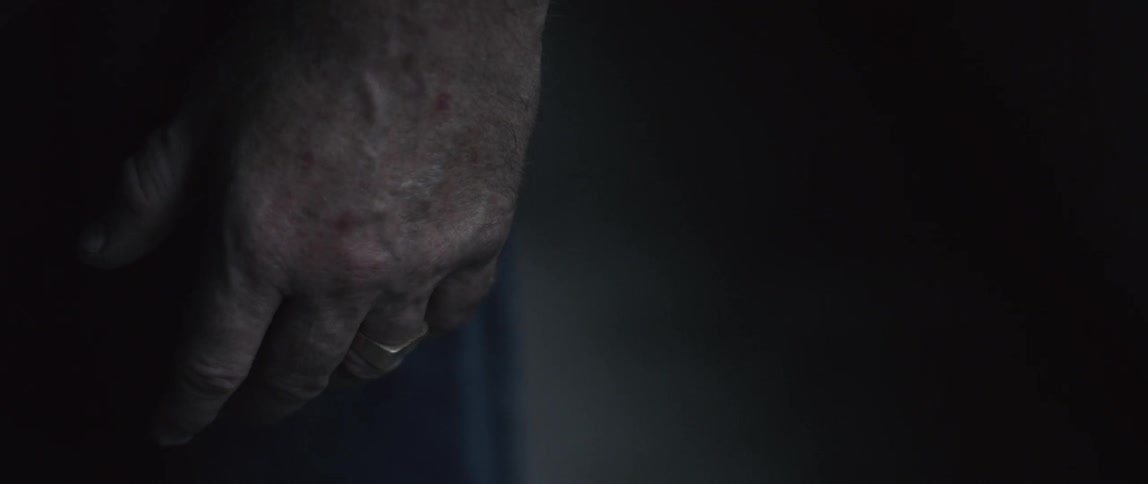 A hand hangs adorned with just a ring