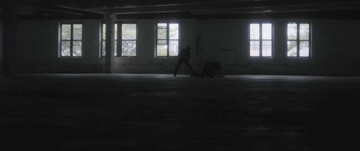 Two men fighting in a and empty room
