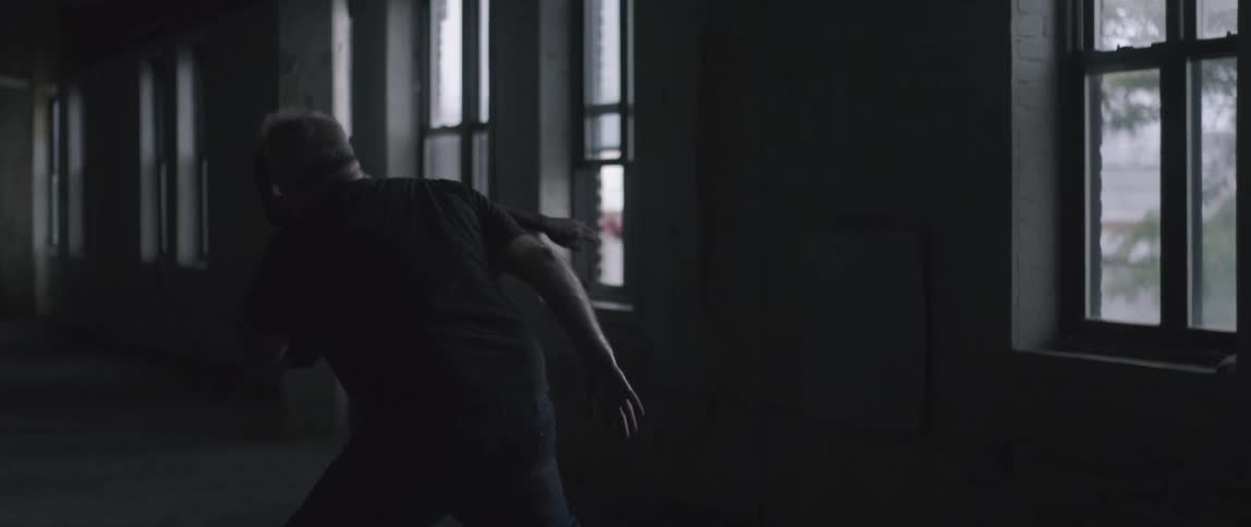 Two men fight near windows inside a building