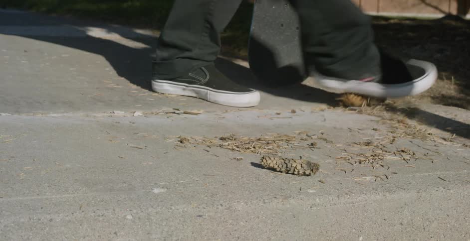 A person stops a skateboard to kick debris out of the way during the day
