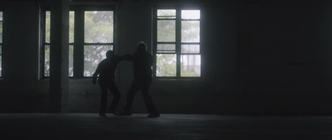 Two men fight in an empty room