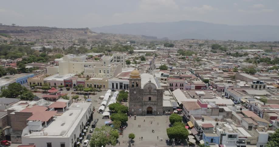 People walk around the square between the town buildings and church