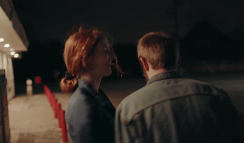 A man and woman walking to a store at night