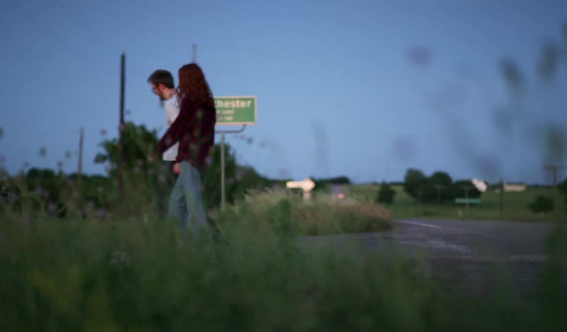 Couple walk across grass at night