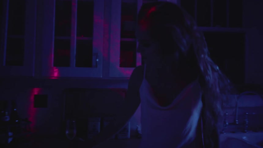 The woman drinks in the dark kitchen