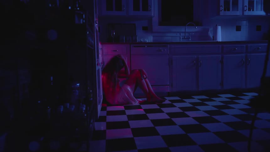 A woman sits in the dark kitchen