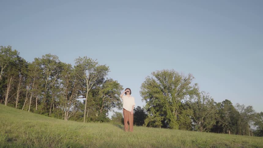 Person standing in a tree lined field