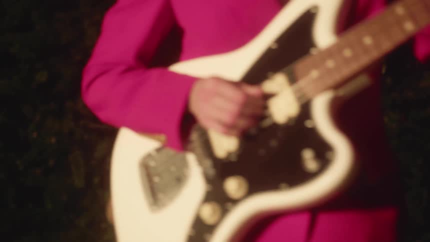 A guitarist dances while playing outside at night
