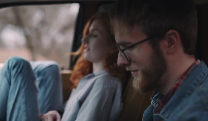 A man and a woman sit in the front seats of a car