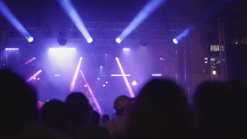 Pink and purple lights on the stage at a concert full of people