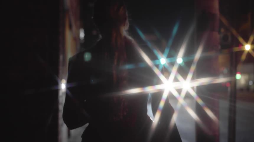 Woman walks down city street at night