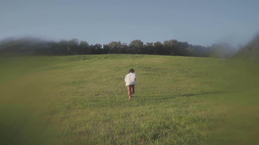 A child is running down the long grassy hill