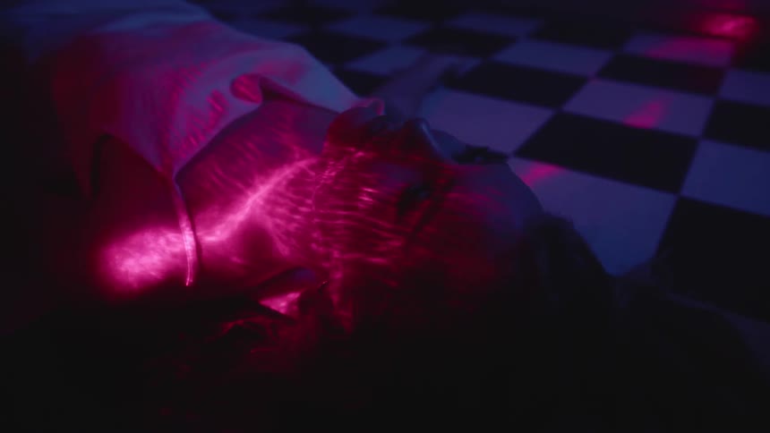 Woman lying down on dance floor and disco lights shine on her face