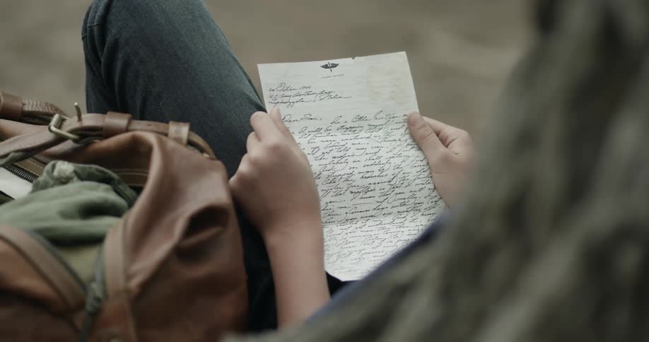 A person sitting and reading a handwritten letter