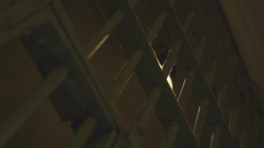 Looking at the ceiling lamp through the gates of a jail cell