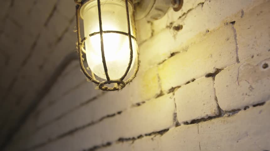 A light glows on the brick wall of a building