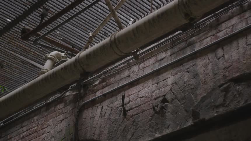 A large pipe hangs from brackets attached to a metal grate
