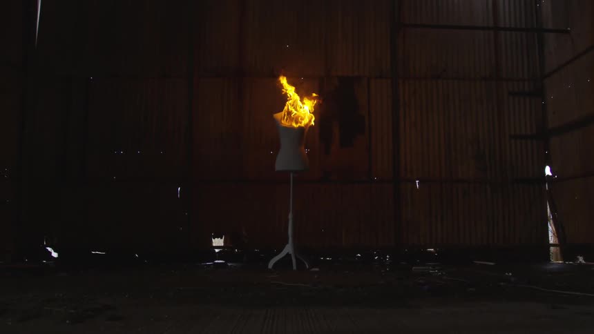 A naked mannequin body is on fire in a warehouse