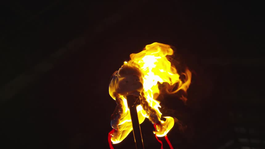 The head of a doll burns on a pole