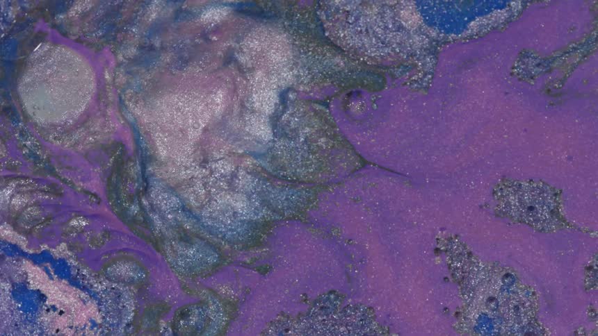 Purple and grey swirls of paint with glitter on top of a liquid