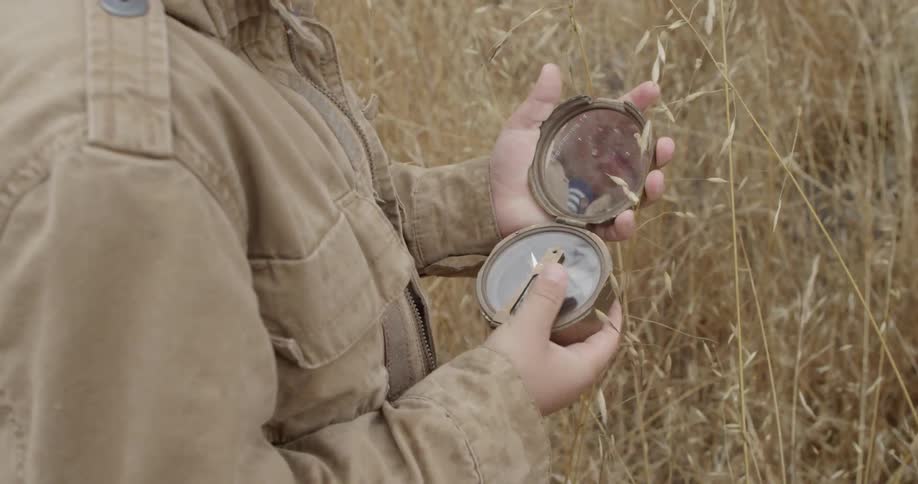 Child roams through a wheat field with a compass