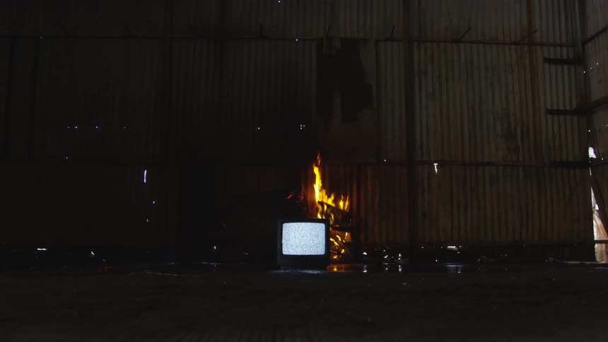 A television is flickering with fire behind it