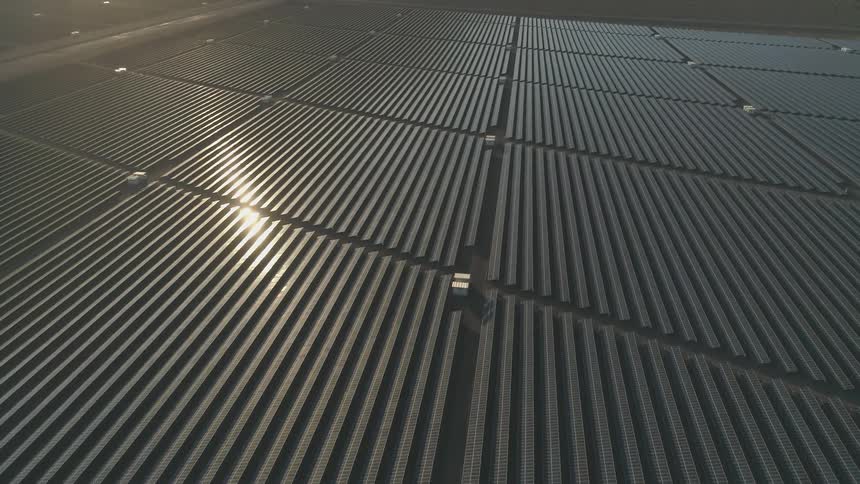 The sun shines across solar panels in a solar farm