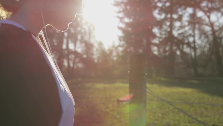 A woman listens to her headphones in the forest