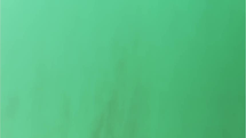 Green dirt slowly falls by the light