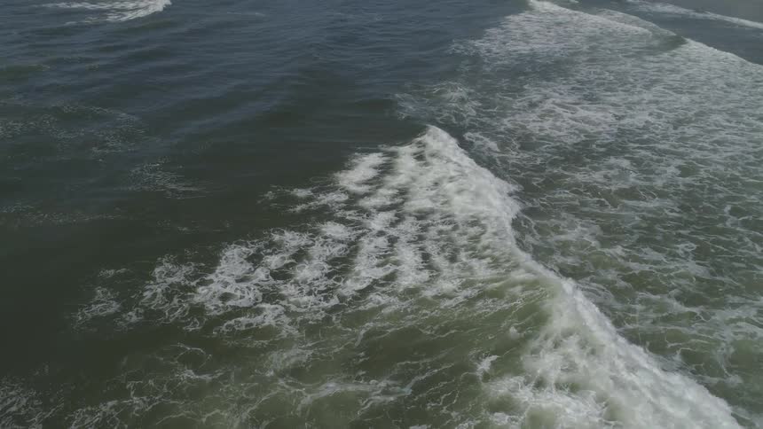 The waves flow towards the beach shore