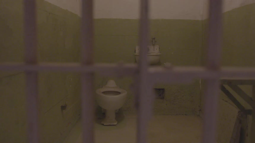 An empty green painted jail cell with no bed