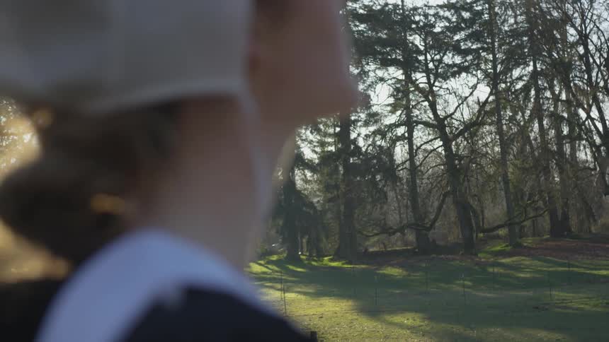 A woman is staring at the forest on a sunny day