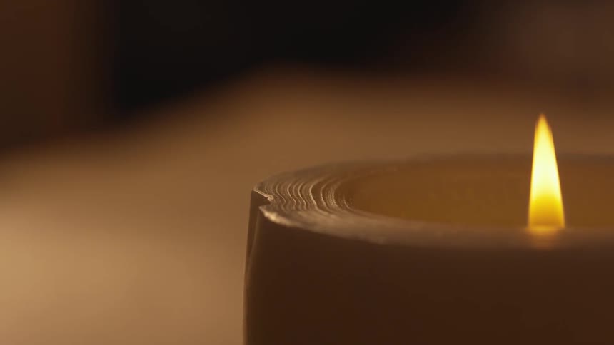 A candle burns on a flat surface