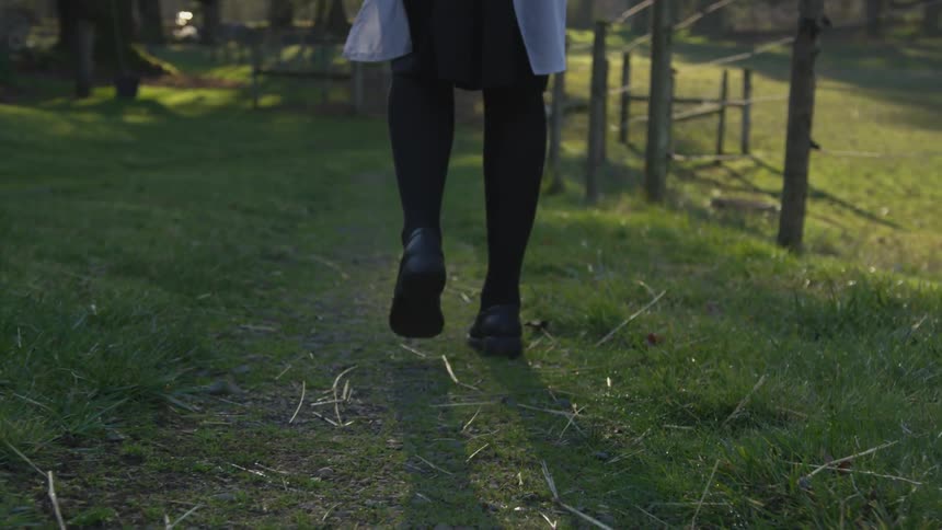 A woman is walking in green grass outdoors
