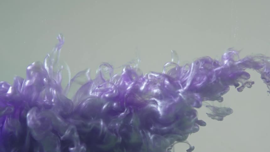 Purple liquid shoots into water and spreads