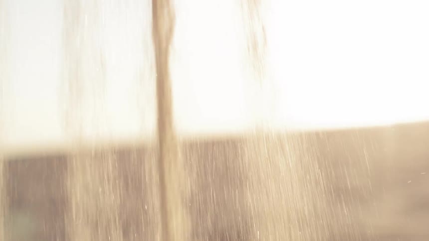 A child scooping up sand and letting it pour back out