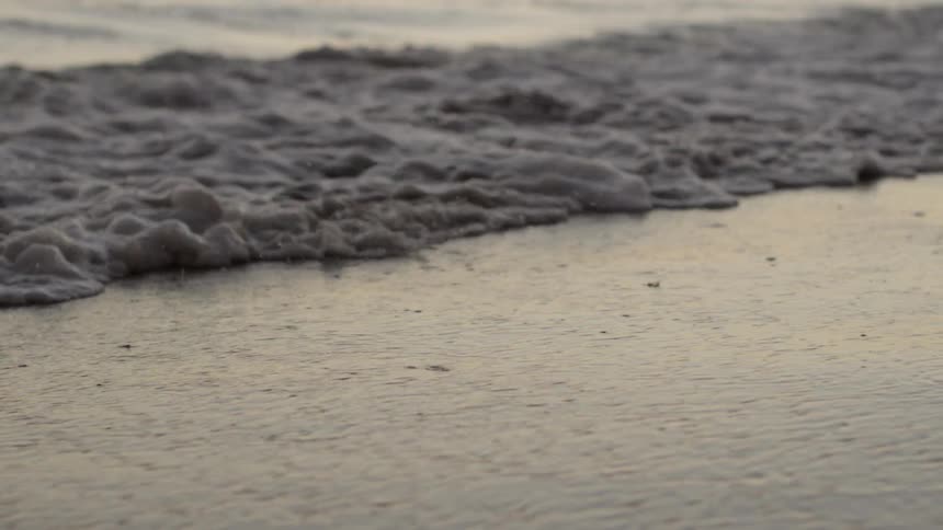 Waves flow and crash into the shore in slow motion