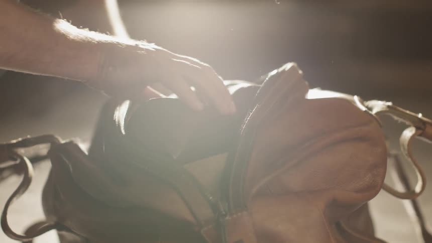A leather carry on bag is opened while resting on a wood floor