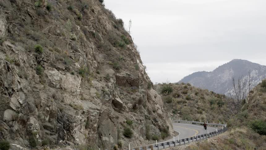 Person driving a bike down a narrow road by a cliff