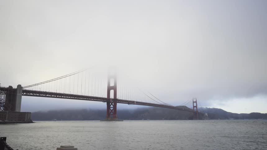 Large bridge over a body of water on a foggy day