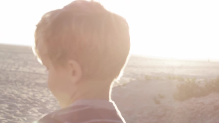 Young child walks on the beach on a sunny day