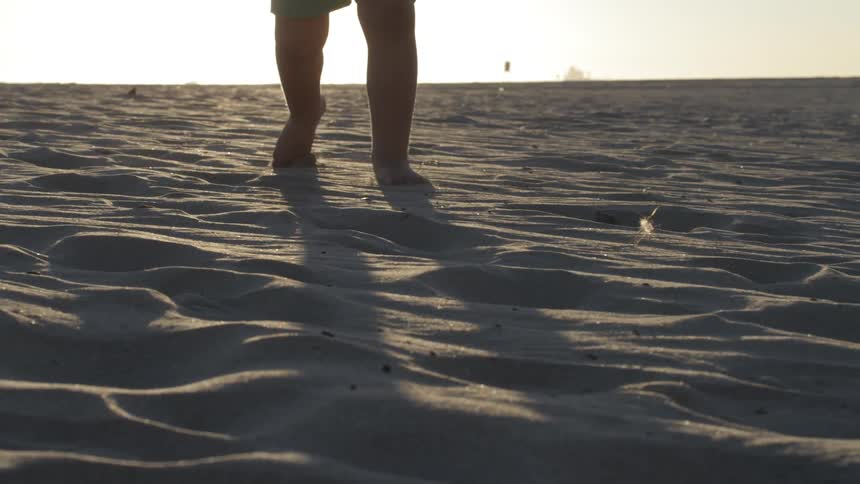 A child running on a sandy beach at sunset