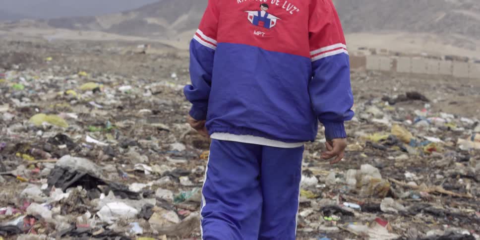 A boy walking through a landfill